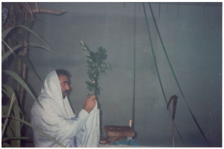 Il Maestro Yisrael Dovid bar Avraham Delle Donne - Benedizione e santificazione della Casa di Preghiera per tutti i Popoli. Sullo sfondo il Bastone del Pastore delle Pecore Smarrite della Casa d’Israele su cui è avvolta la pelle del capretto poggiata sulla tomba dei Patriarchi ad Ebron; su questa pelle è stato fatto salire, per ungerlo con l’olio con settanta pietre attorno ai suoi piedi, il Maestro Yisrael.